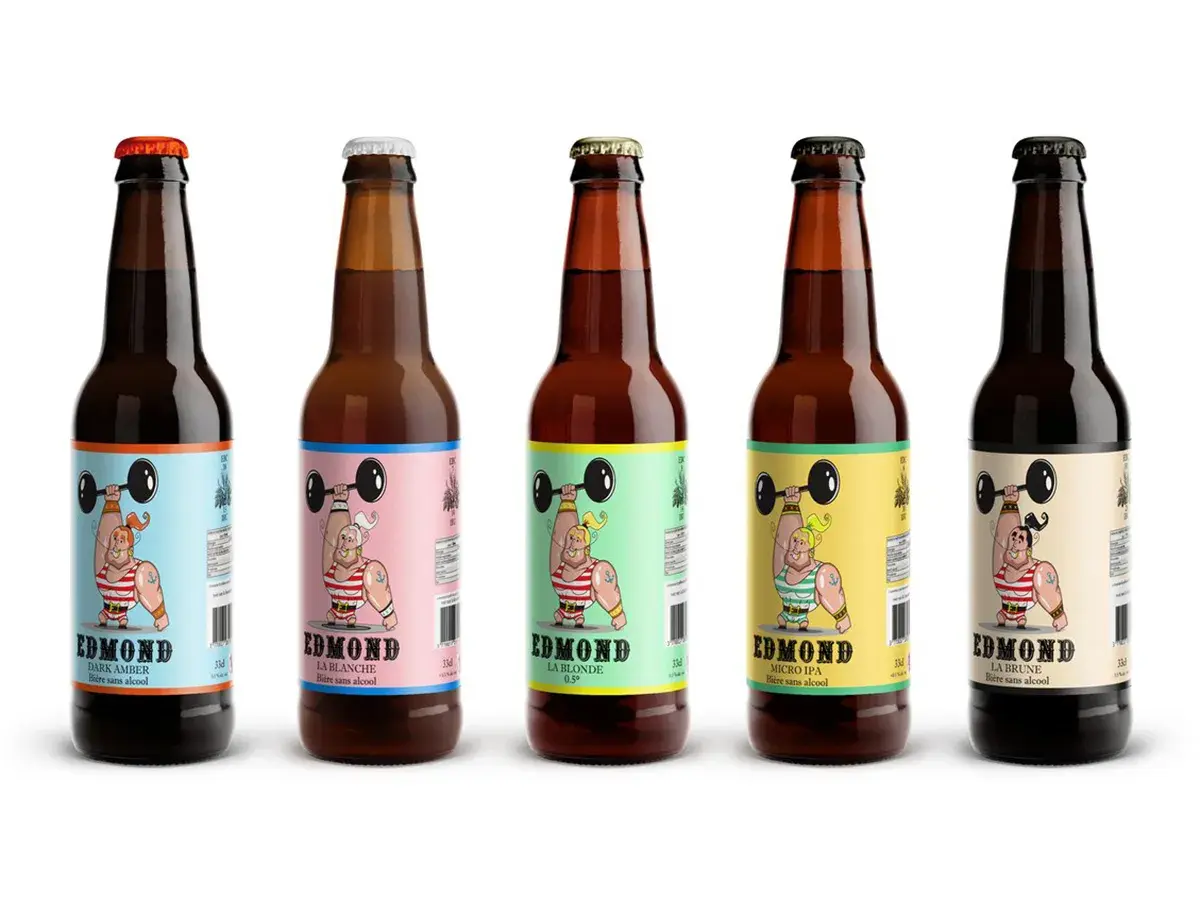 Cinq bouteilles de bière algérienne Edmond, aux étiquettes colorées représentant un haltérophile musclé.