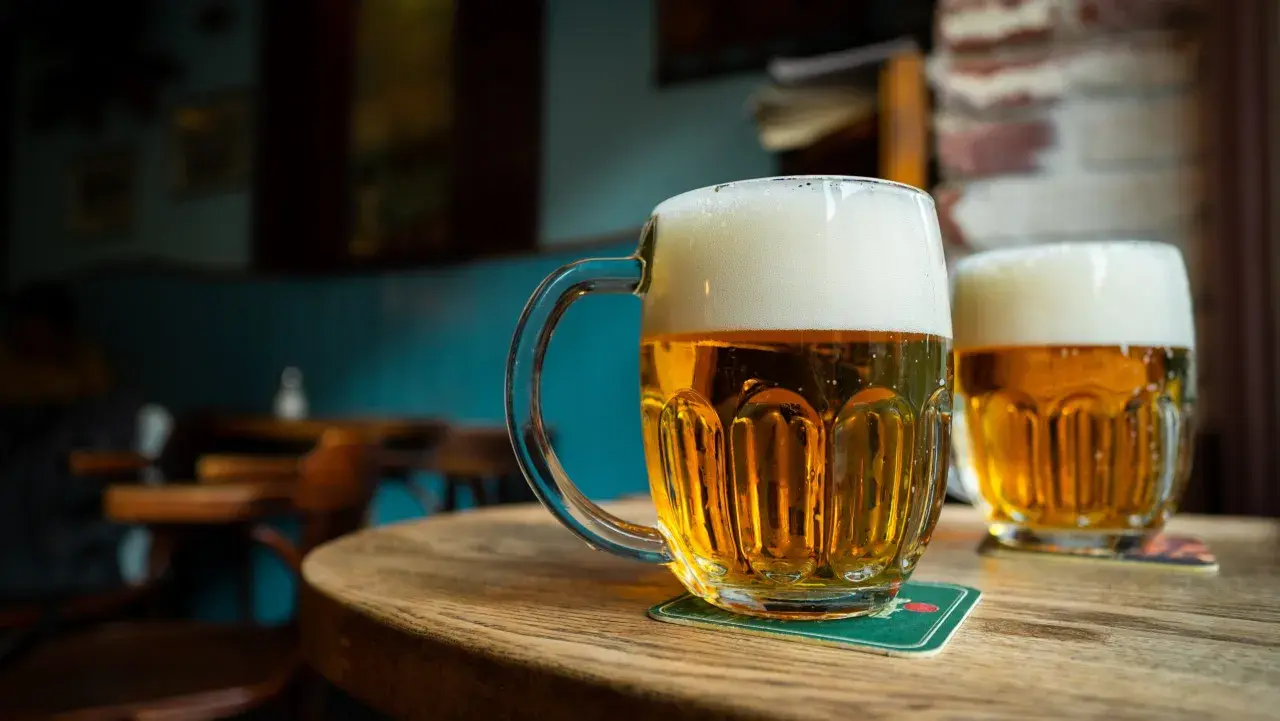 Deux chopes de bière pression mousseuse sur une table en bois. Le prix d'une bière pression est raisonnable pour ce moment de détente.