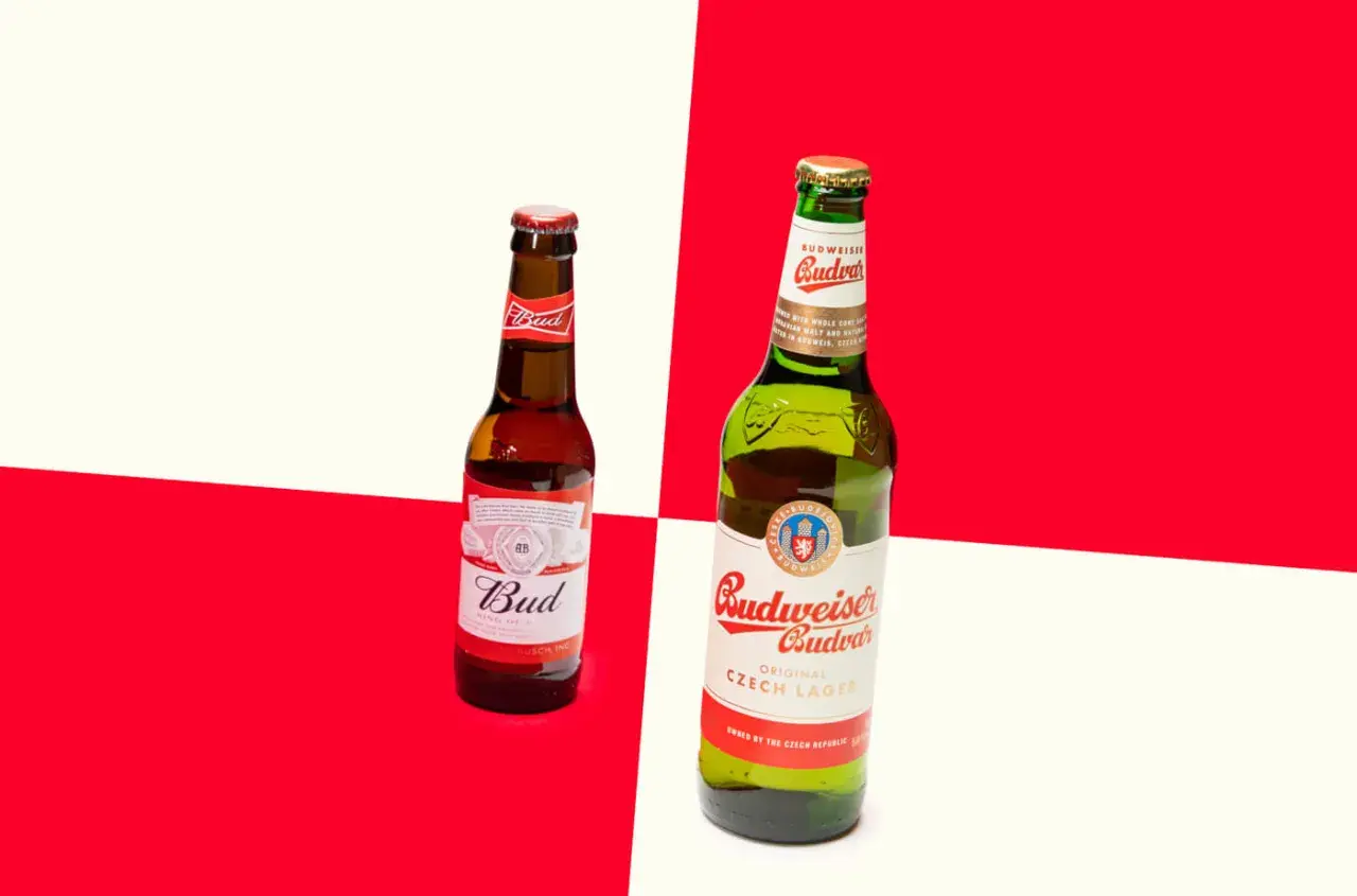 Deux bouteilles de bière, une Bud et une Budweiser Budvar, sur fond rouge et blanc.