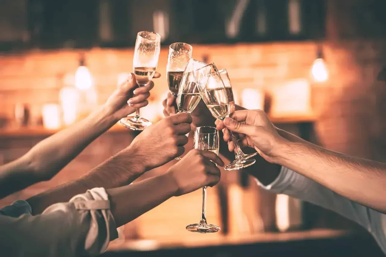 Des mains lèvent des flûtes de champagne pour trinquer. Une belle façon de célébrer, comme pour apprendre comment trinquer en allemand avec un "Prost !".