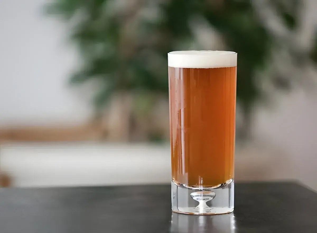 Un verre de bière ambrée, parfaite pour une recette de pale ale maison. La mousse blanche couronne la boisson.