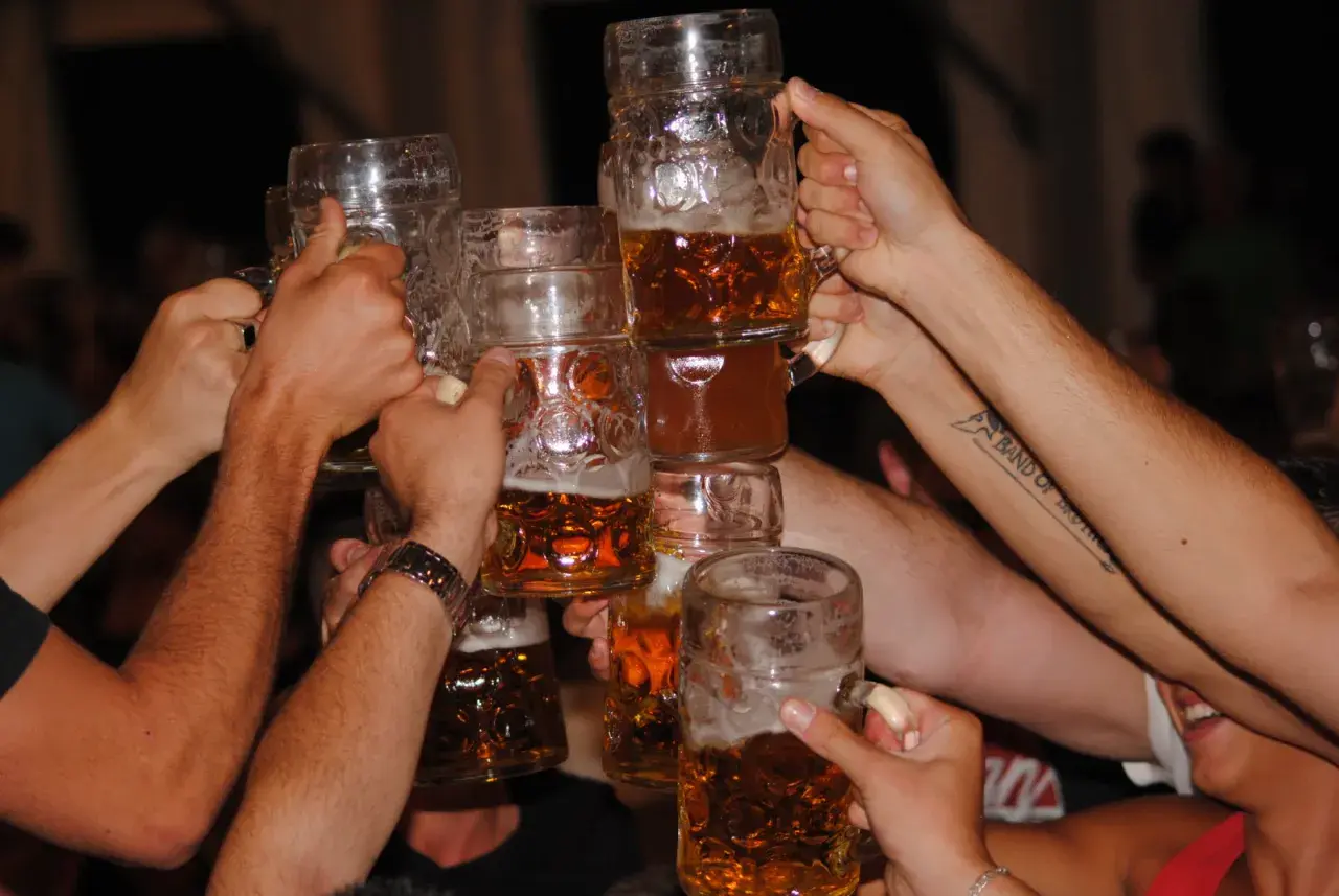 Des mains lèvent des chopes de bière pour trinquer, une joyeuse fête de la bière en cours.