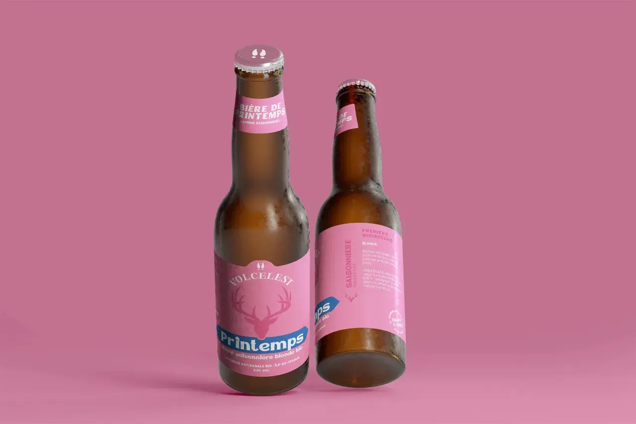 Deux bouteilles de bière artisanale "Printemps" sur fond rose. L'une met en avant le nom "Printemps" avec un cerf stylisé.