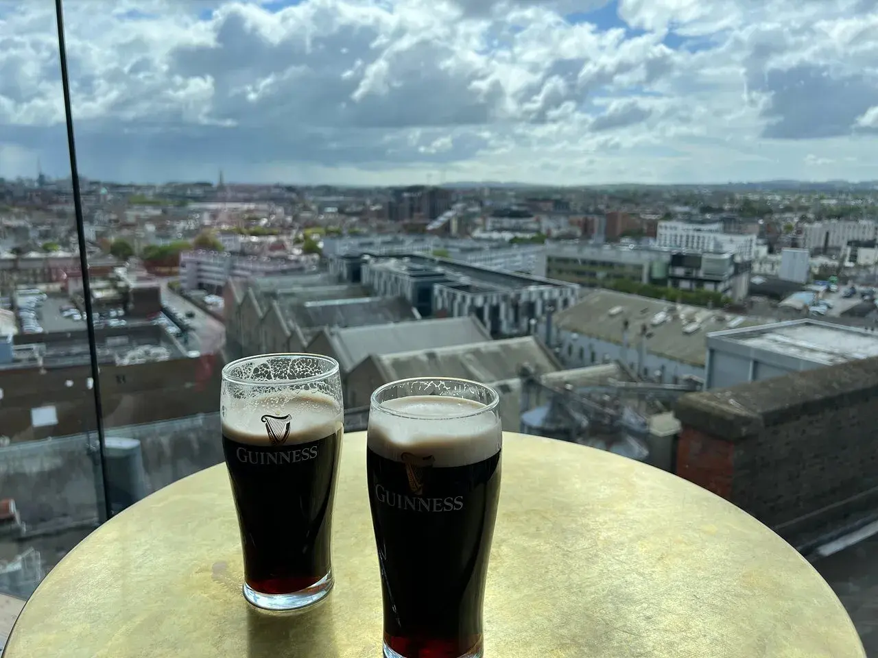 Deux bières Guinness sur une table dorée, avec une vue panoramique sur Dublin.