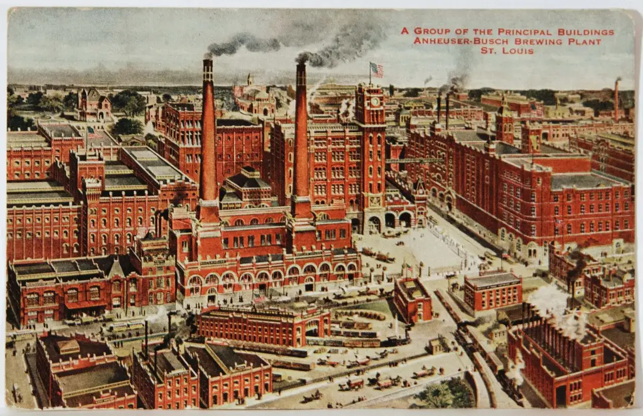 Vue aérienne de l'usine Anheuser-Busch à St. Louis, berceau de la bière Bud. Les cheminées dégagent de la fumée, signe d'une production active.