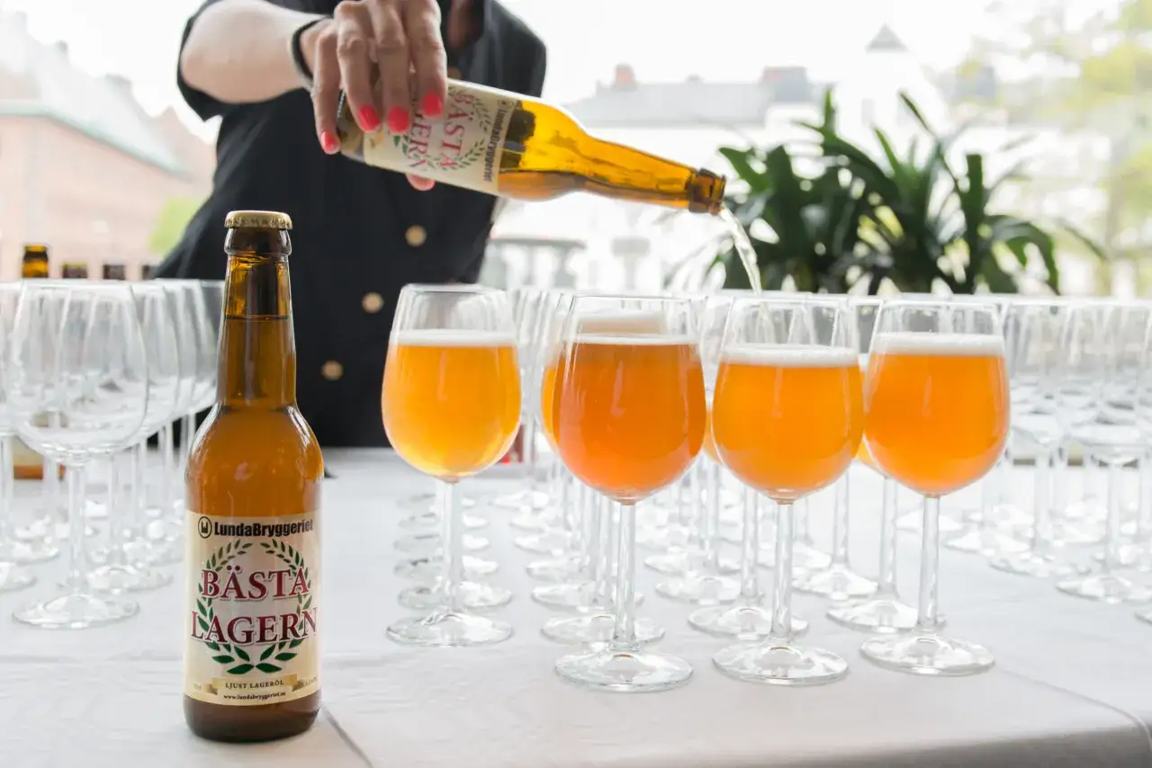 Une personne verse la bi&egrave;re su&eacute;doise connue, B&auml;sta Lagern, dans des verres &agrave; pied align&eacute;s.