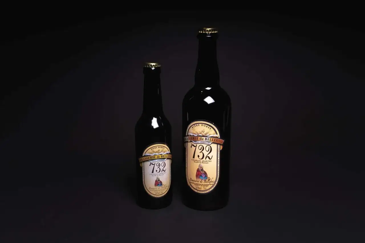 Deux bouteilles de bière dorée de la Brasserie de Bellefois, l'une plus petite que l'autre, se dressent sur un fond sombre.