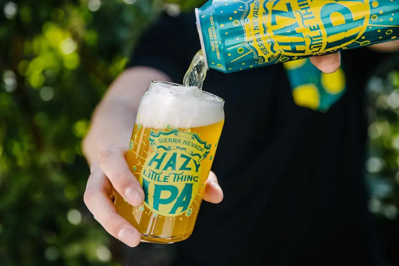 Une bière trouble, une Hazy Little Thing IPA, est versée d'une canette dans un verre.
