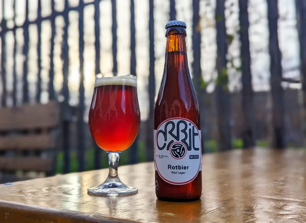 Verre de bière rouge et sa bouteille sur une table en bois. La bière rouge, une Rotbier, est prête à être dégustée.