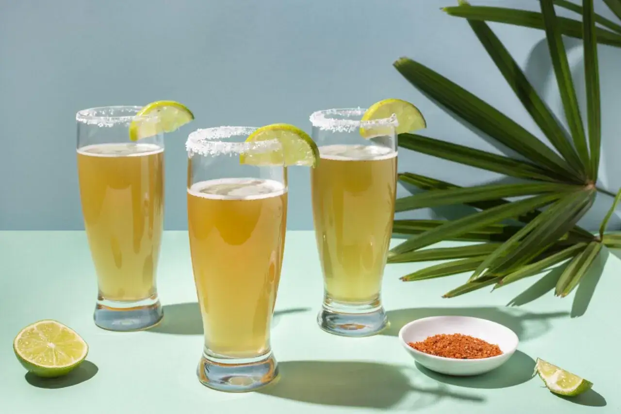 Trois verres de bière avec des bords salés et des quartiers de citron vert, prêts pour une dégustation. El tequito vs desperados, un choix rafraîchissant.