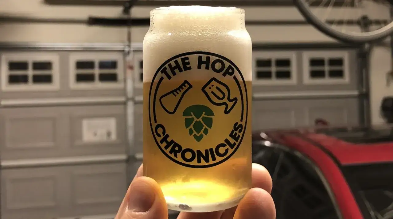 Un verre de bi&egrave;re blonde avec une mousse abondante, orn&eacute; du logo 