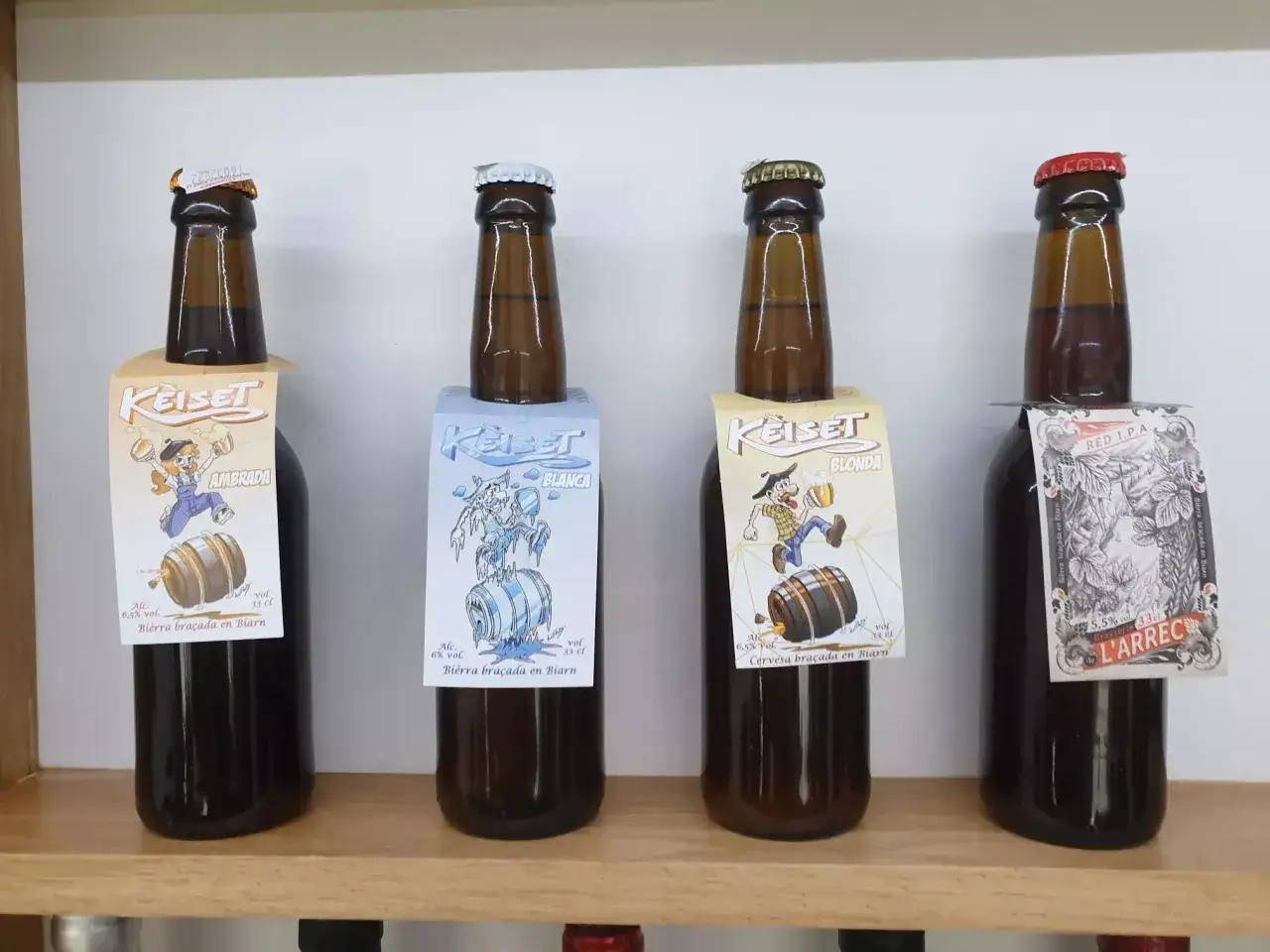 Quatre bouteilles de bière Keiset, dont une Red IPA, sont alignées. L'une des bières est une 
