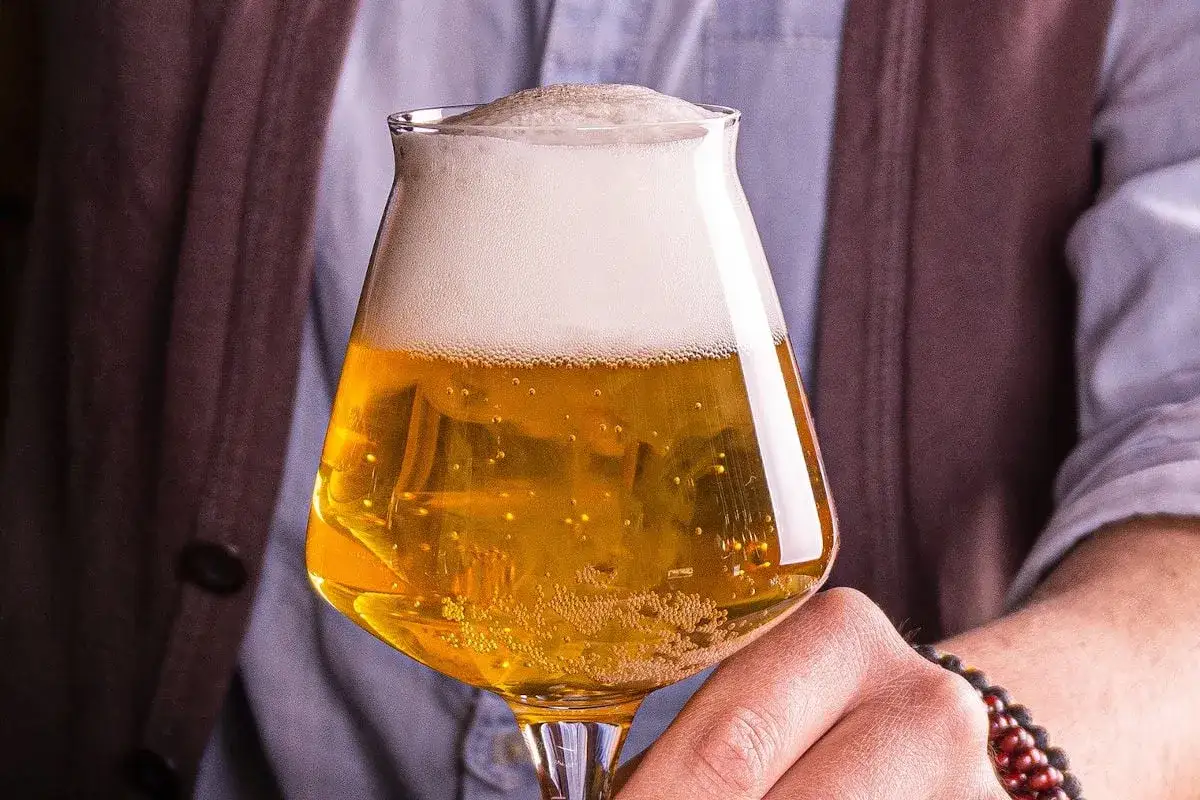 Un verre de type de bière blonde, pétillante et dorée, avec une mousse blanche et onctueuse.