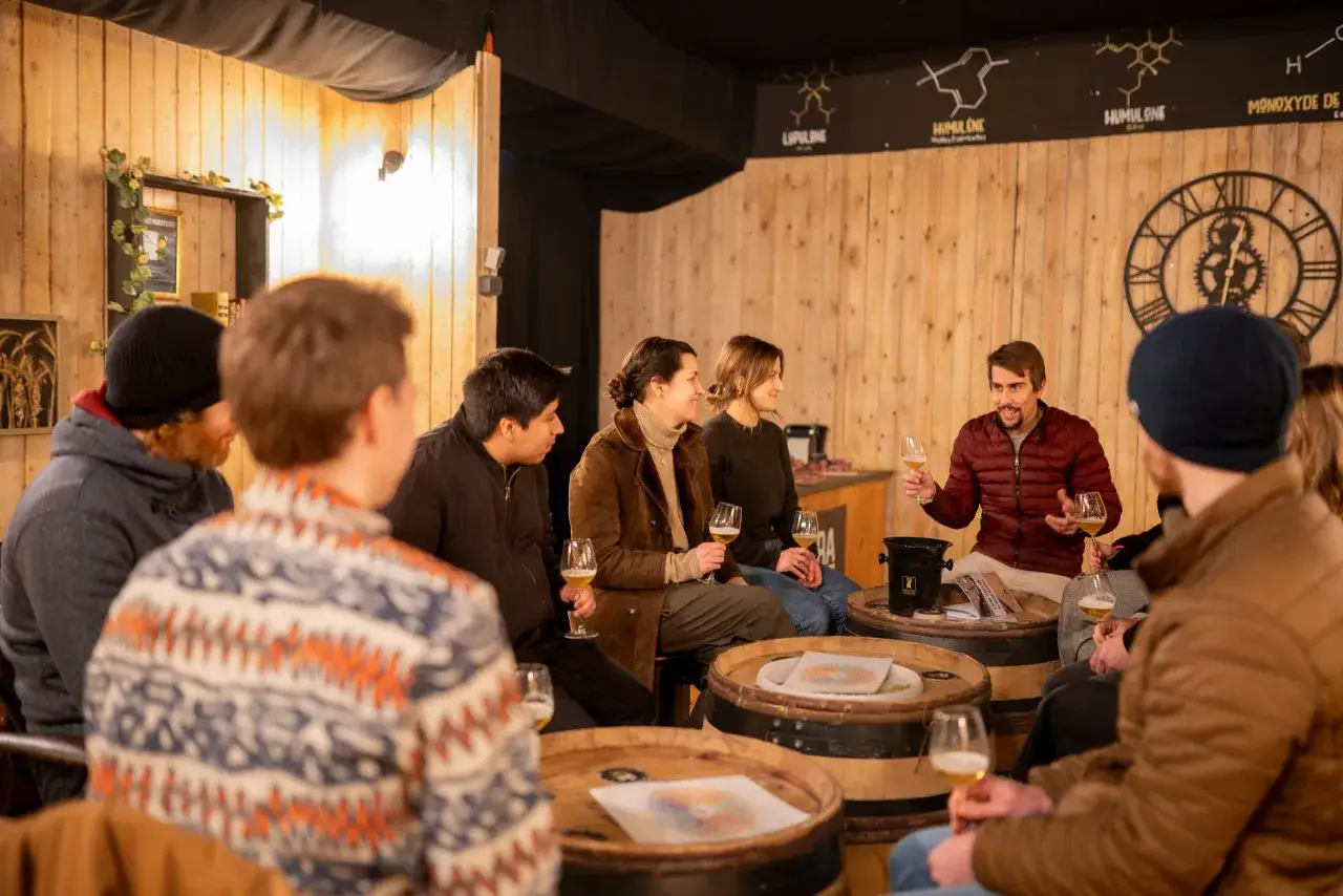 Un groupe d'amis profite d'une dégustation, un accord met bière est en cours. Ils sont assis autour de tonneaux en bois, chacun tenant un verre de bière.