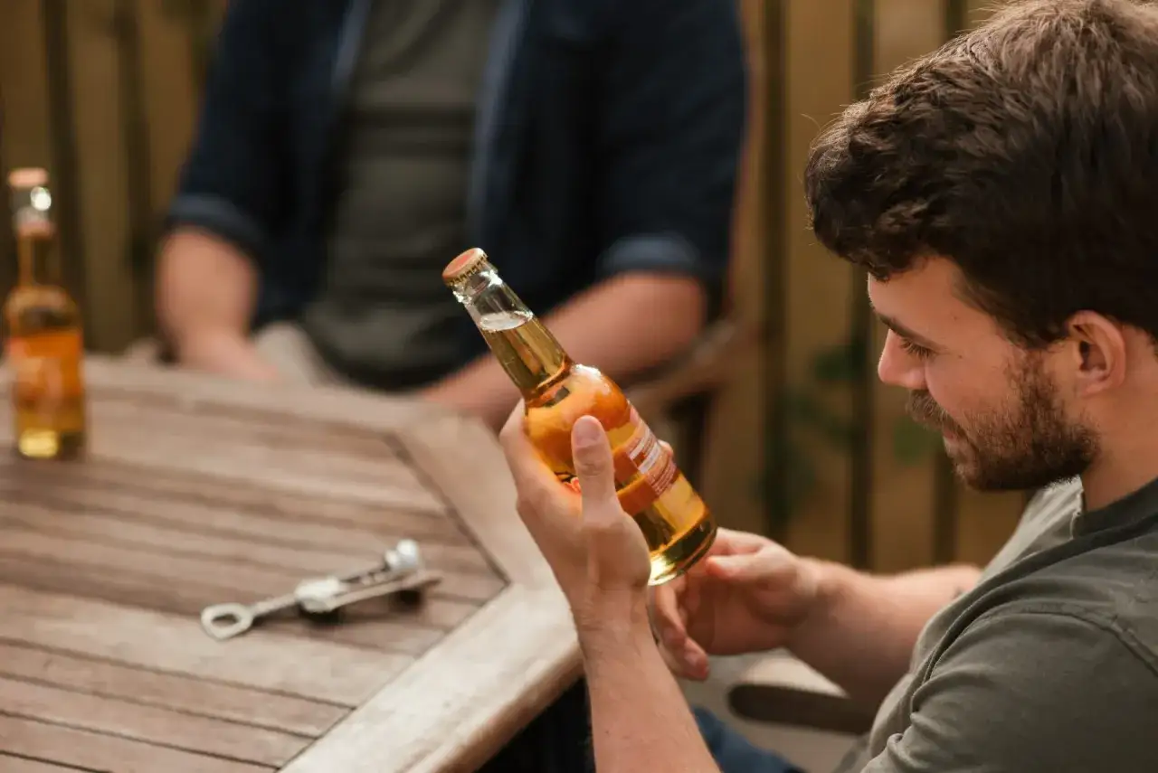 Un homme tient une bouteille de la meilleure bière normande, prêt à la déguster avec un ami.