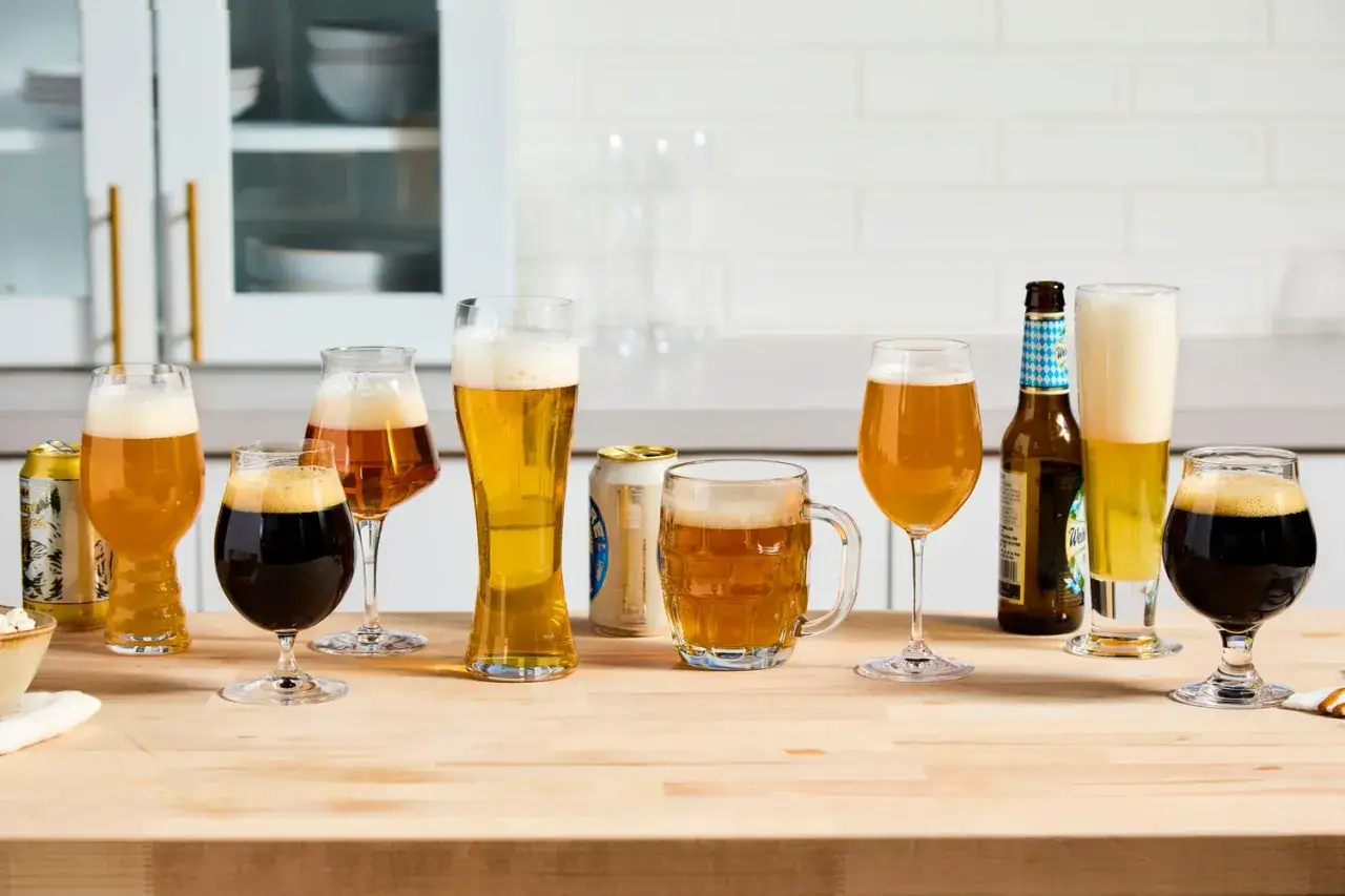 Diverses bi&egrave;res, dont une bi&egrave;re irlandaise connue, sont pr&eacute;sent&eacute;es dans des verres et des canettes sur un comptoir en bois.
