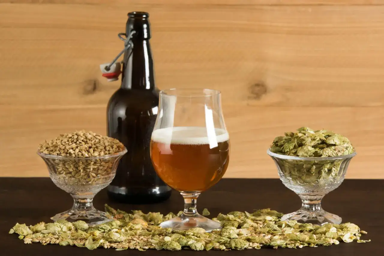 Bi&egrave;re ambr&eacute;e dans un verre, entour&eacute;e de houblon et de malt. Une bouteille &agrave; bouchon m&eacute;canique se tient derri&egrave;re. Un vrai biere smash !