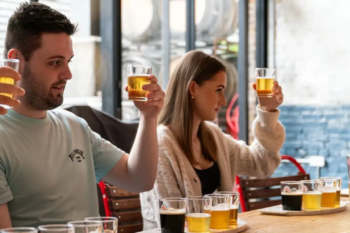 Dégustation de bières Camden. Un homme et une femme lèvent leurs verres, souriants, lors d'une dégustation de bières.