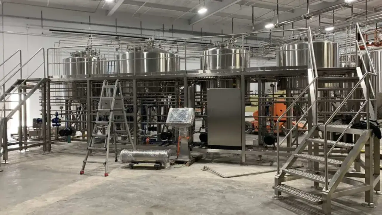 Installation d'une brasserie américaine avec cuves en inox, escaliers et tuyauterie complexe.
