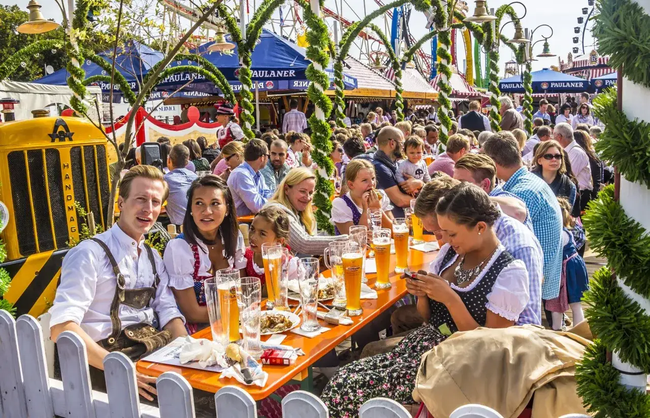 Fête bavaroise à Paris : des gens en tenue traditionnelle dégustent de la bière sous des guirlandes.