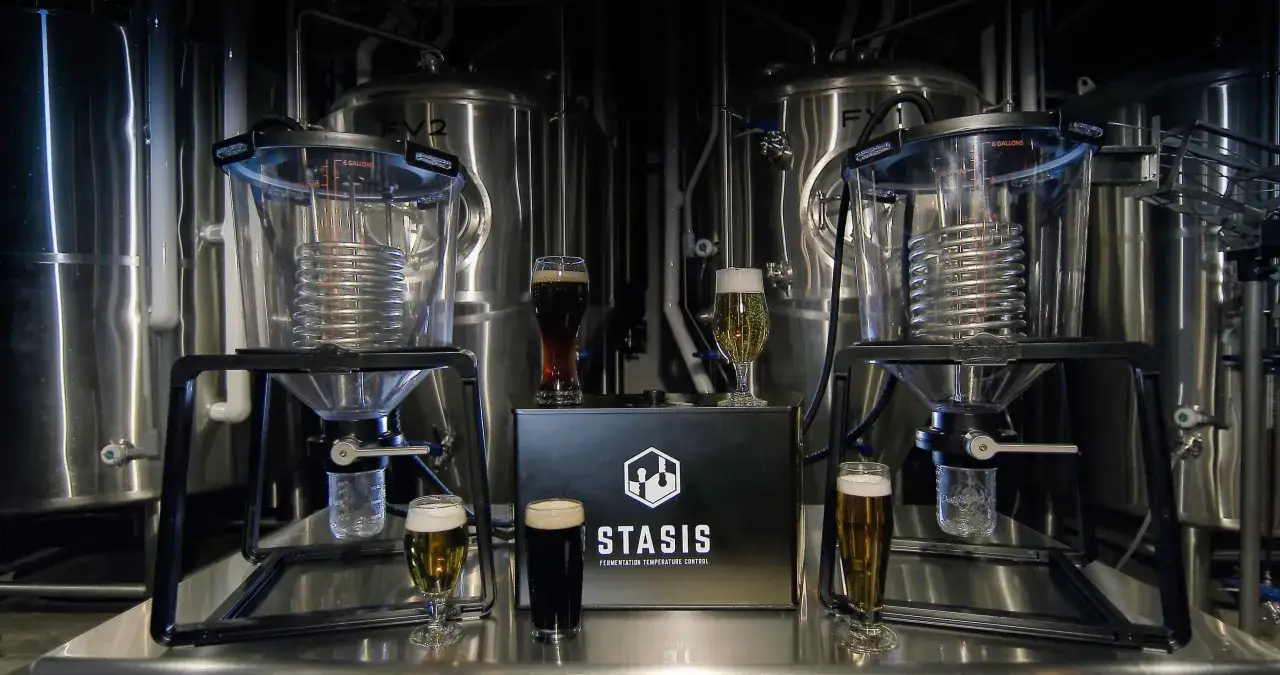 Contr&ocirc;le pr&eacute;cis de la temp&eacute;rature fermentation bi&egrave;re avec des fermenteurs STASIS. Des verres de bi&egrave;re sont pr&eacute;sent&eacute;s devant les cuves.