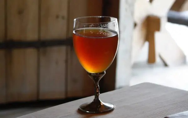 Verre de bière norvégienne ambrée, posé sur une table en bois.
